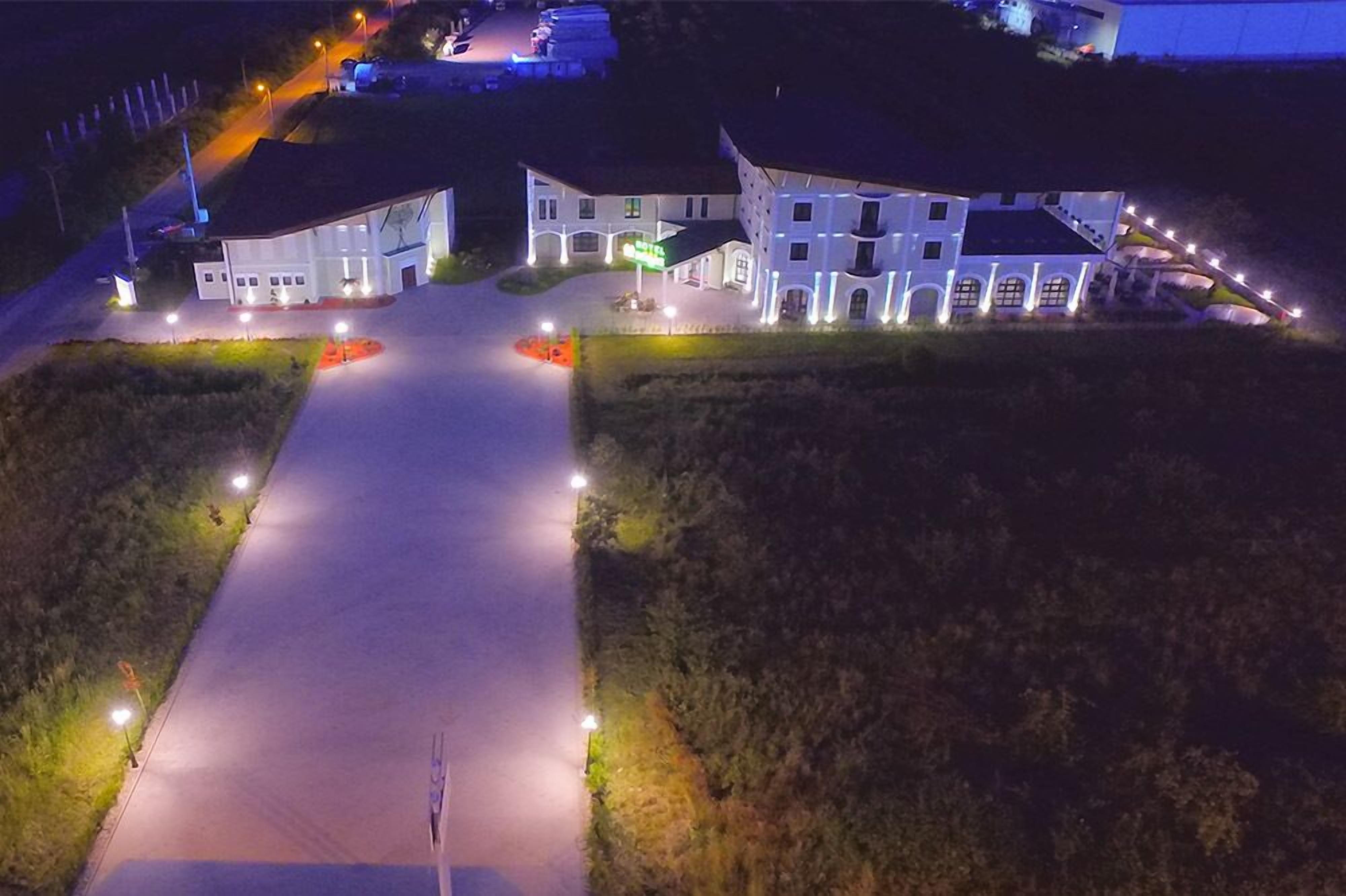 Un grand bâtiment bien éclairé, doté d’une cour intérieure, entouré d’espaces paysagers et d’une route pavée qui y mène.