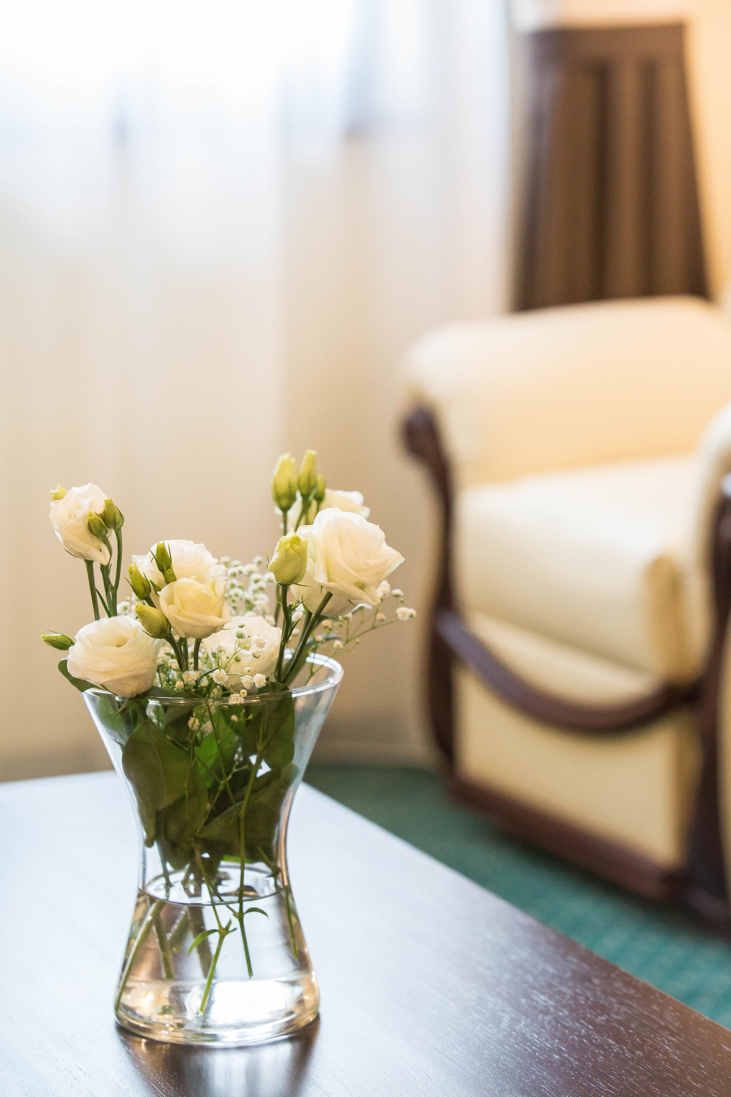 Eine klare Glasvase mit weißen Blumen auf einem Holztisch.