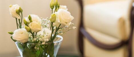 Un jarrón de cristal transparente con flores blancas sobre una mesa de madera.