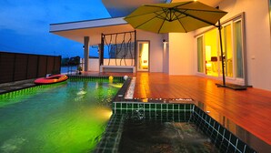 A modern house with a swimming pool, a covered patio, and a large umbrella. - Jira Pool Villa (Hua Hin)
