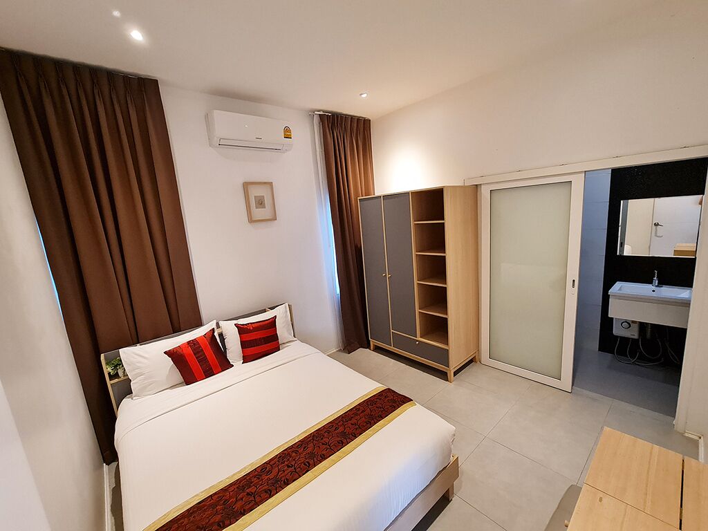 A hotel room with a bed, wardrobe, and a bathroom with a sink and mirror.