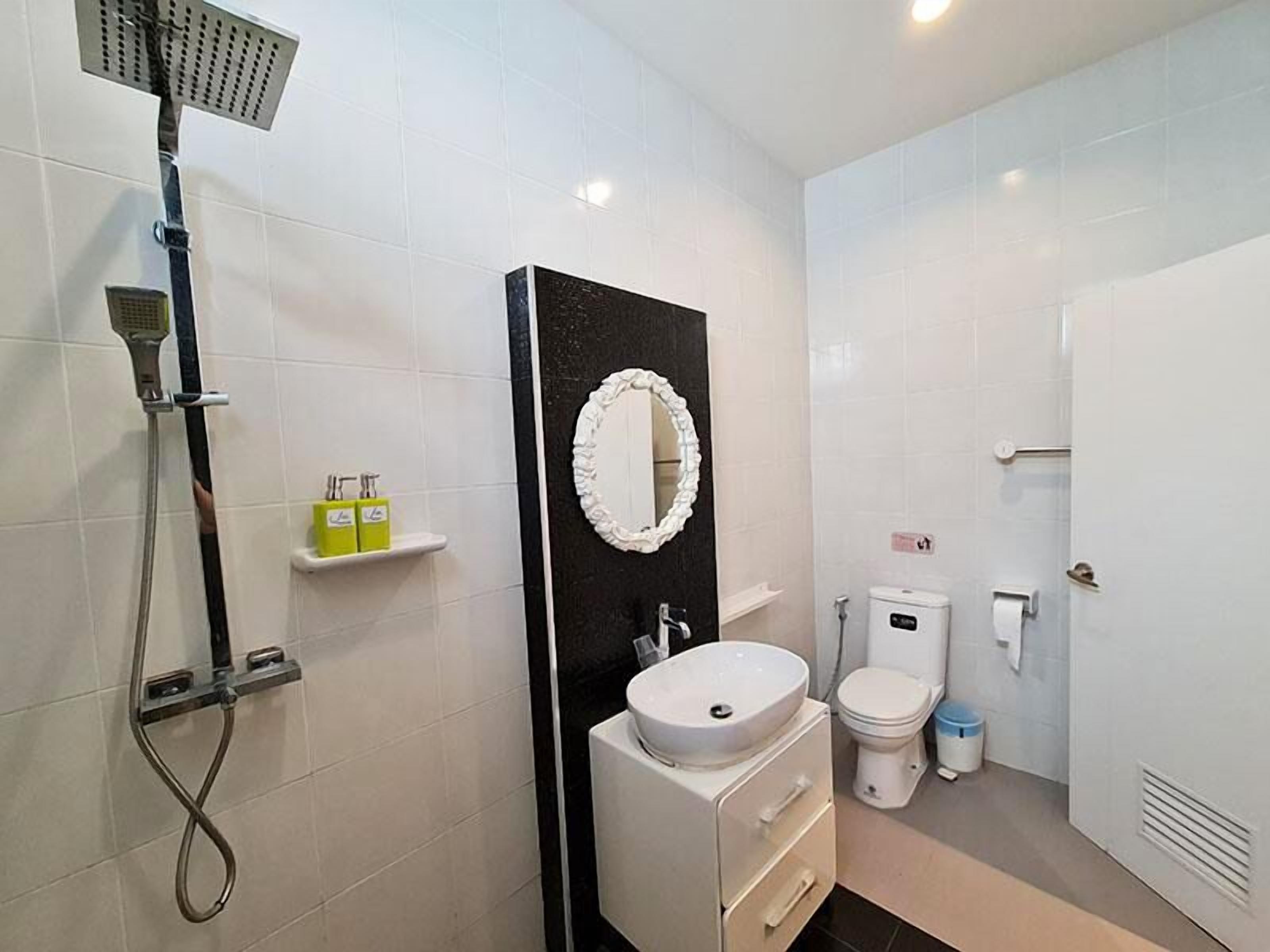 A bathroom with a shower, toilet, sink, and a mirror.