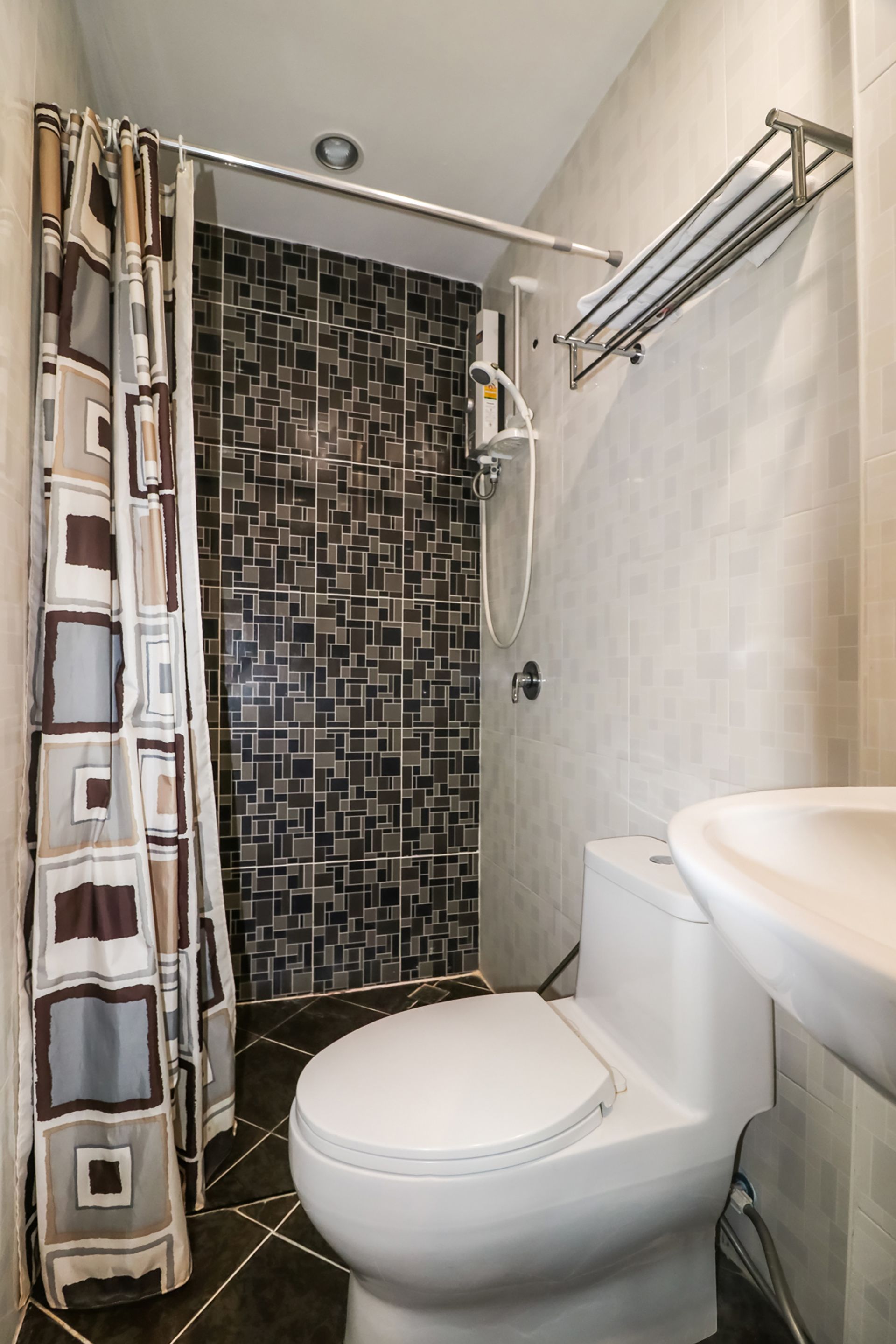 A bathroom with a white toilet, a shower with a glass door, and a tiled shower wall.