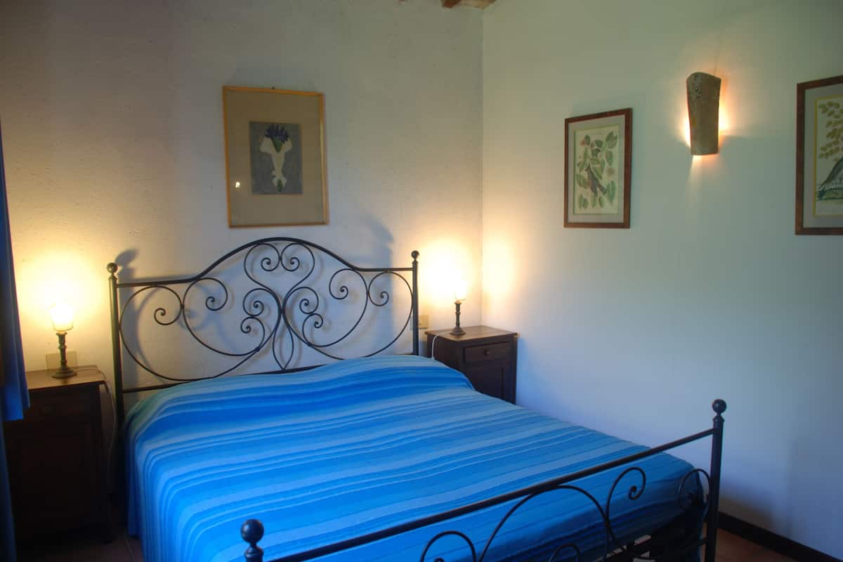 A bed with a blue striped bedspread, two bedside tables with lamps, and framed pictures on the wall.