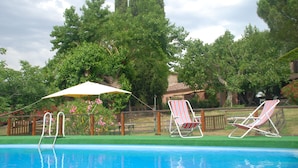 A swimming pool with two lounge chairs and a sun umbrella. - Agriturismo Podere Conte Ràcani (Amelia)
