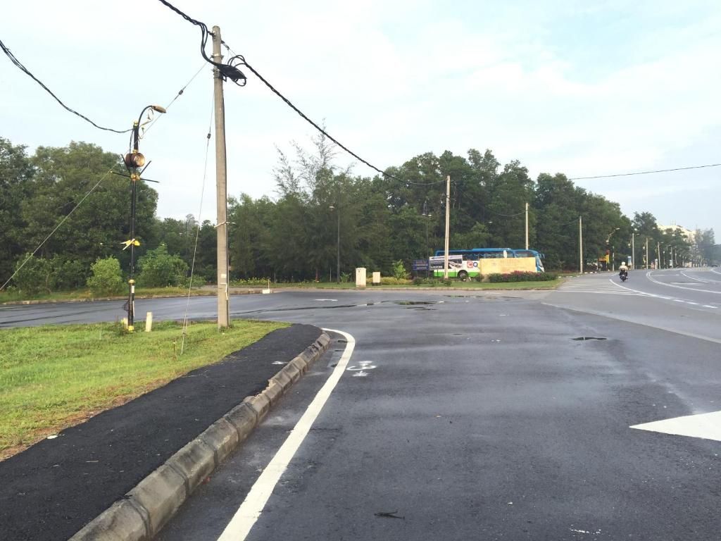 Uma estrada com ciclovia, faixa de pedestres e um motociclista.