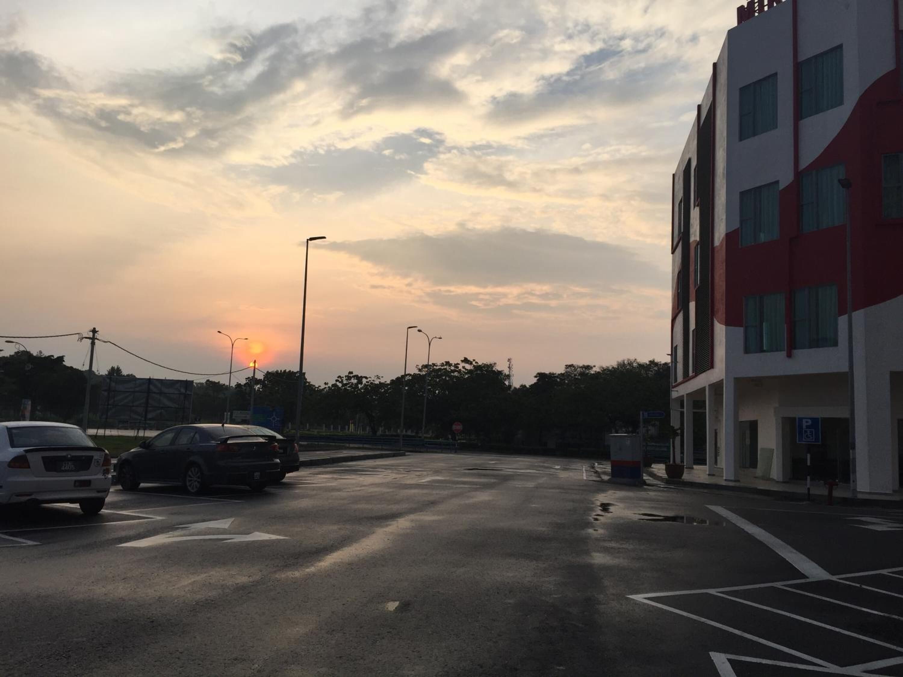 A parking lot with cars and a building with a red and white facade.