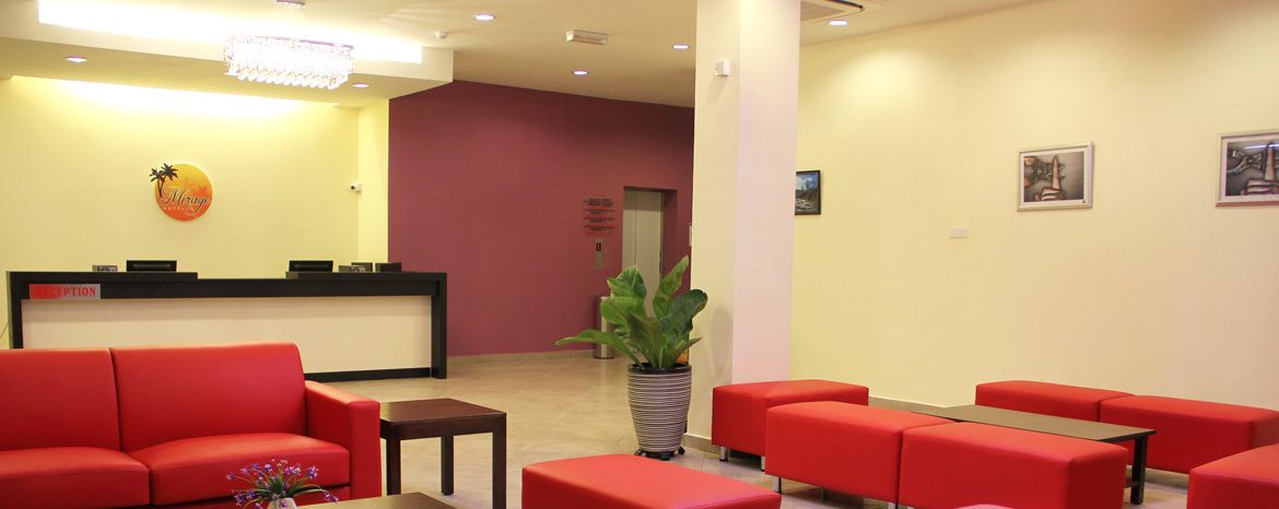 A reception area with a reception desk, red seating, and a potted plant.