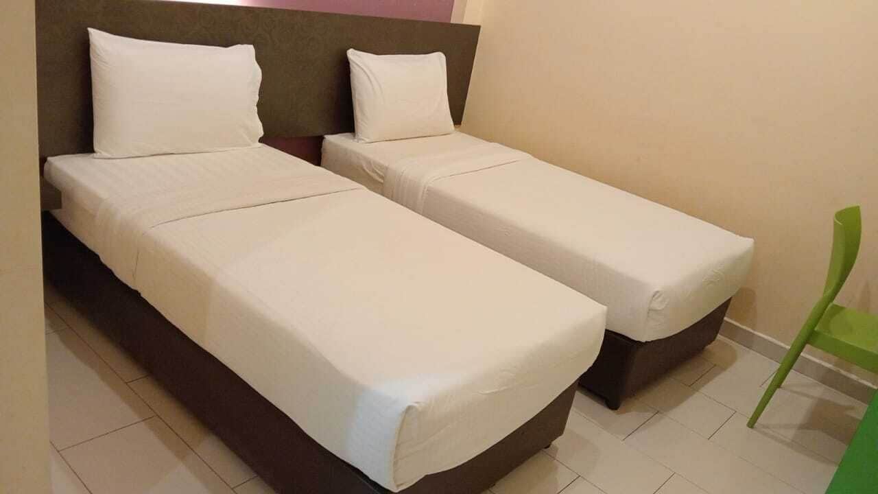 A room with two single beds, a green chair, and a headboard.