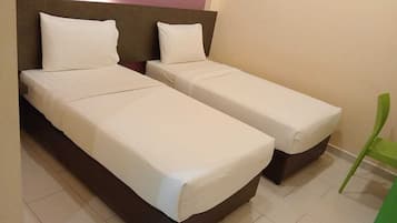 A room with two single beds, a green chair, and a headboard.