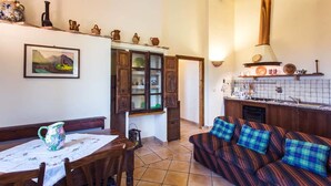 Una cocina acogedora con armarios de madera, una mesa de comedor con sillas y un sofá con cojines de cuadros.