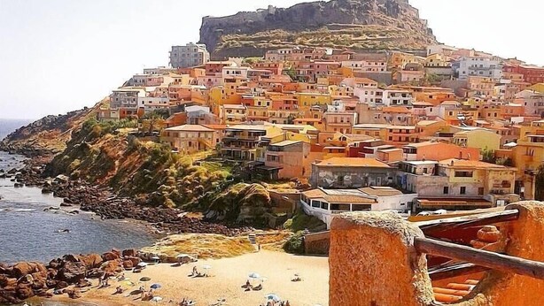 A coastal town with a prominent hilltop fortress, terracotta-roofed buildings, and a sandy beach with umbrellas. - Antica Pensione Pinna (Castelsardo)