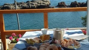 A table set with breakfast items including pastries, a cup, and a jug, overlooking the sea. - Antica Pensione Pinna (Castelsardo)