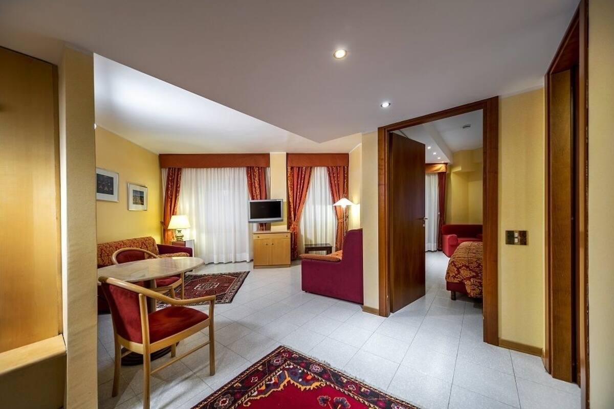 Une chambre d’hôtel comprenant un coin repas, une télévision, un canapé et un lit.