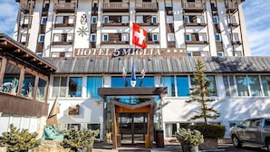 A hotel with a modern facade, balconies, and a Swiss flag.