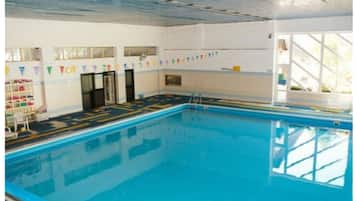 Una piscina al coperto con corsie ben delimitate, una scala e un pavimento piastrellato.
