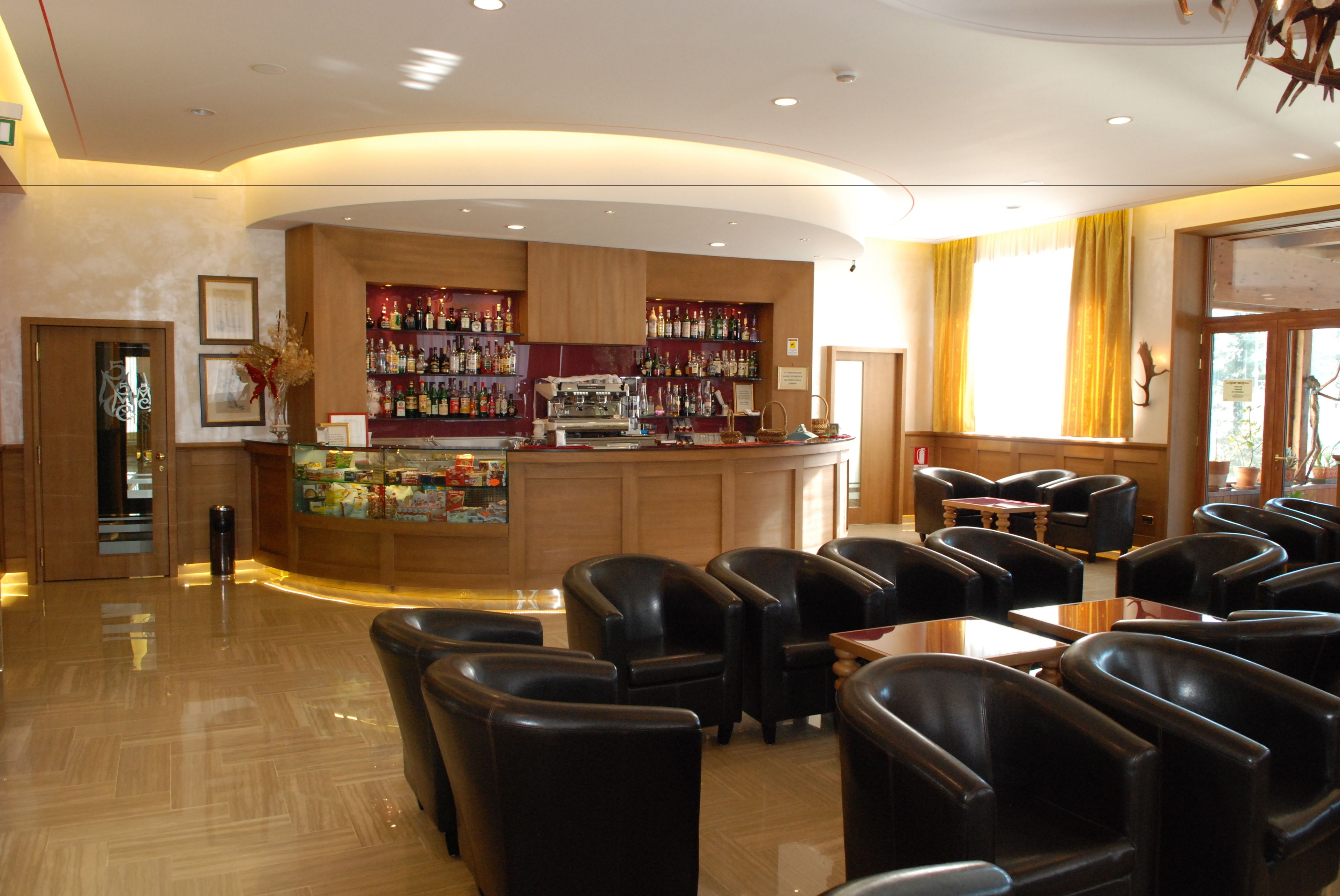 A bar area with a curved counter, black leather chairs, and a polished wooden floor.