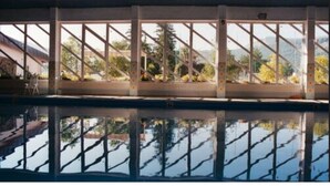 A swimming pool with a clear view of the surrounding landscape through large windows.
