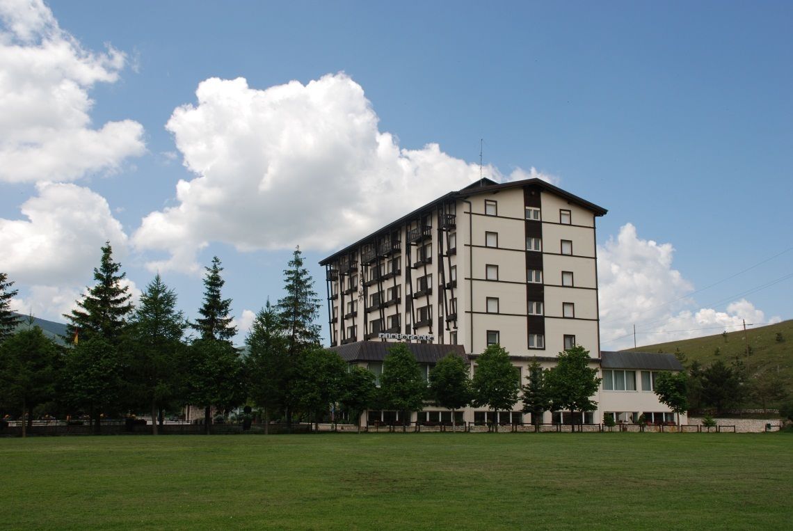 Un edificio de varios pisos con techo plano y un balcón en el segundo nivel.