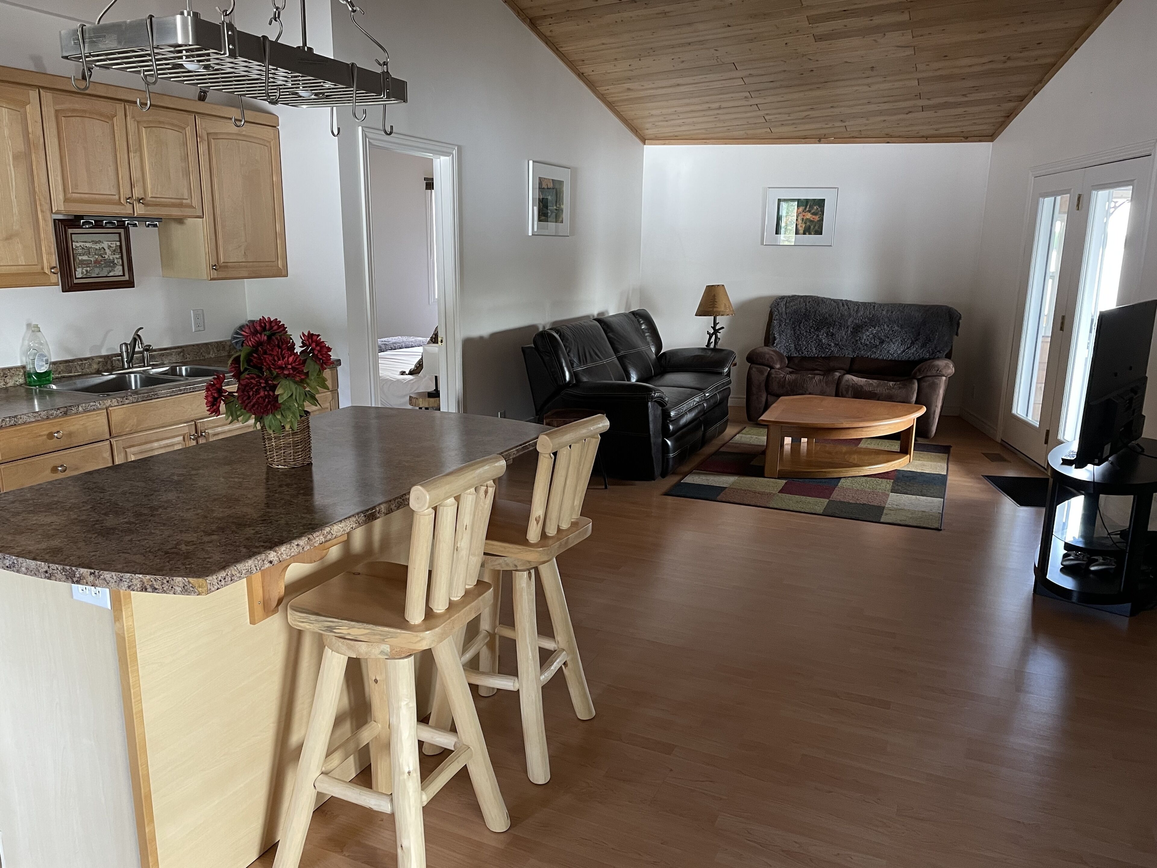 A spacious living area with a kitchen, wooden flooring, and a dining area with a bar.
