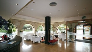 A spacious lobby with a reception desk, seating area, and a large pillar. - Hotel Felisa Spa (Santillana del Mar)