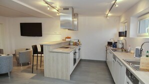 A modern kitchen with a central island, built-in appliances, and a dining area with chairs.