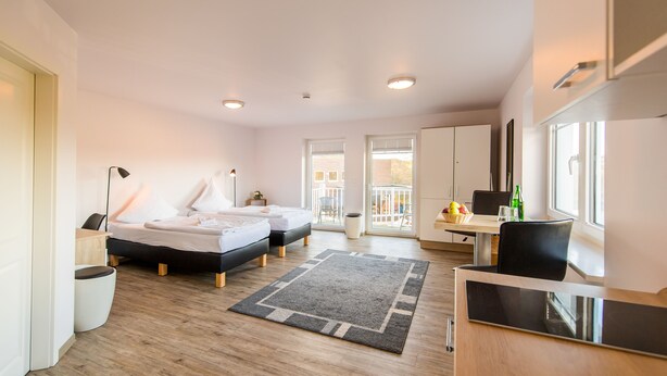 A modern hotel room with two beds, a desk, a chair, and a balcony.