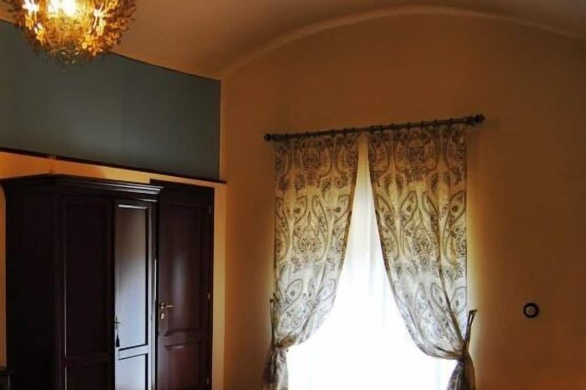 A bedroom with a bed, a wardrobe, a rug, and a window with curtains.