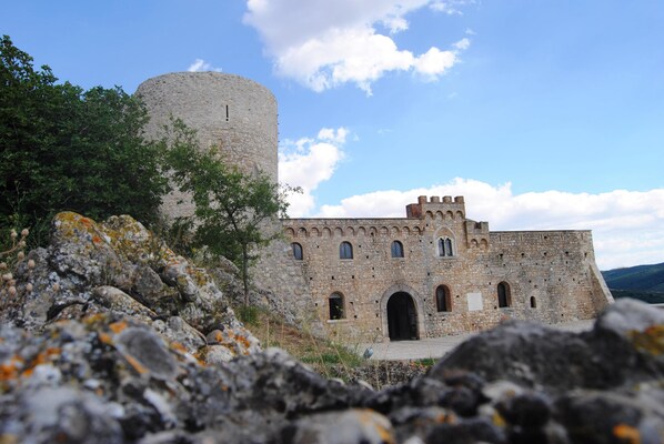 A historic stone building with a round tower, arched windows, and a fortified entrance.