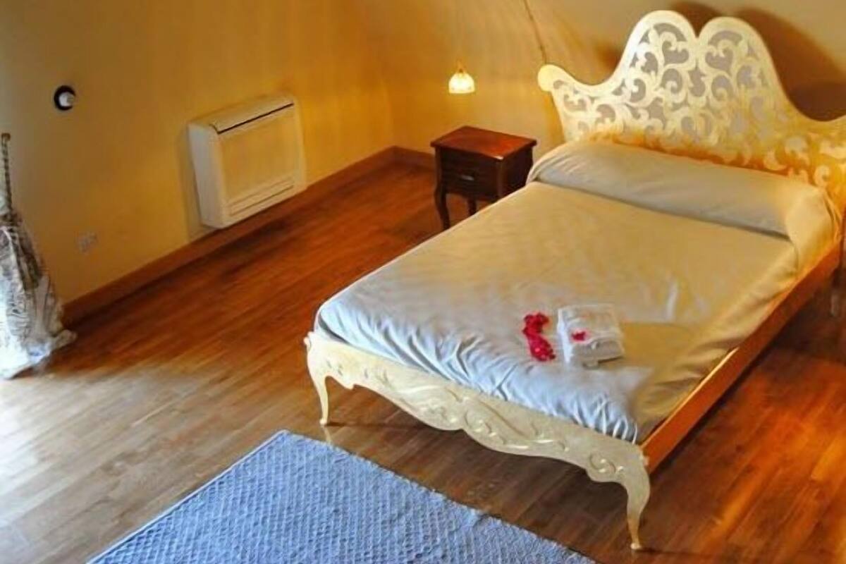 A bedroom with a bed, a nightstand, a lamp, and a radiator.