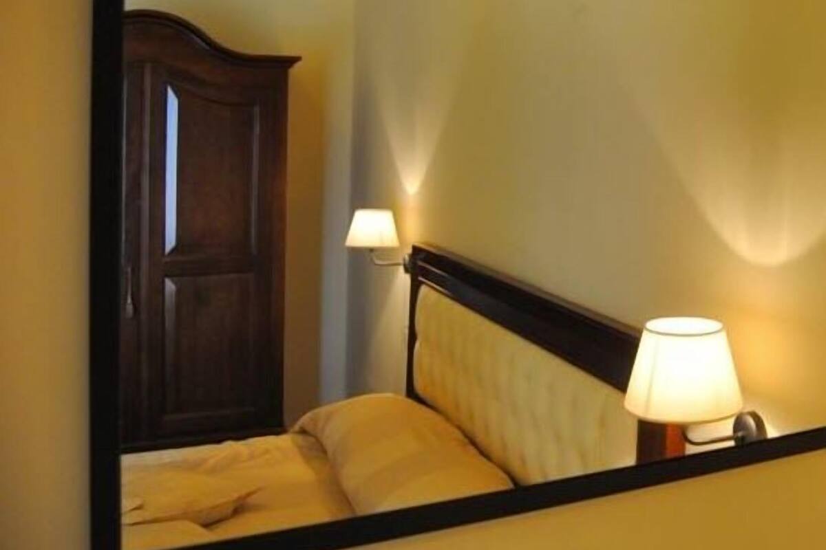 A bedroom with a wooden headboard, a bed, and two bedside lamps.