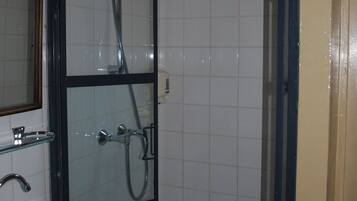 Ett badrum med en dusch som är avskärmad med glasväggar, ett handfat och en spegel.