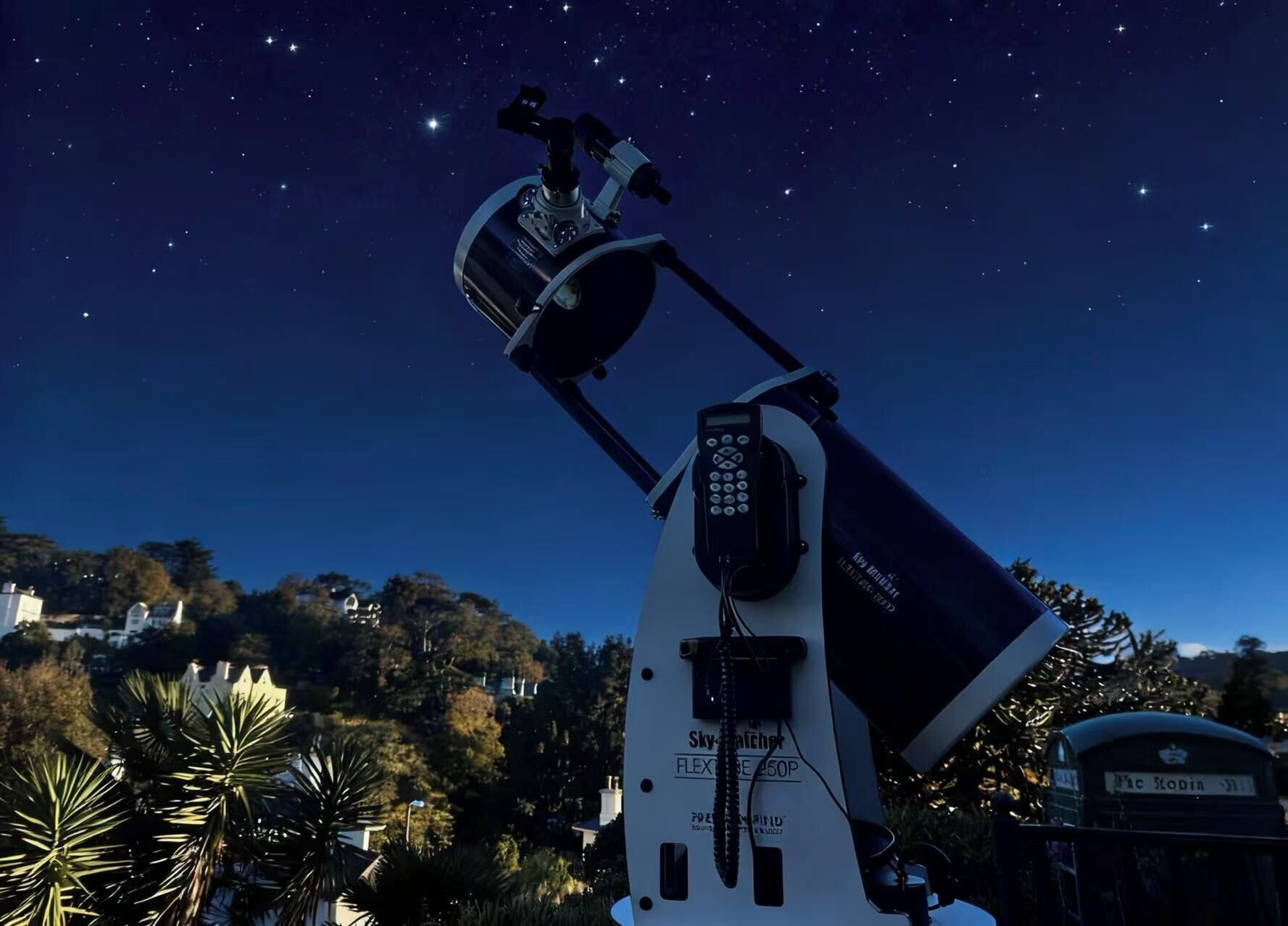 Un telescopio con panel de control y cúpula, frente a un cielo nocturno estrellado.