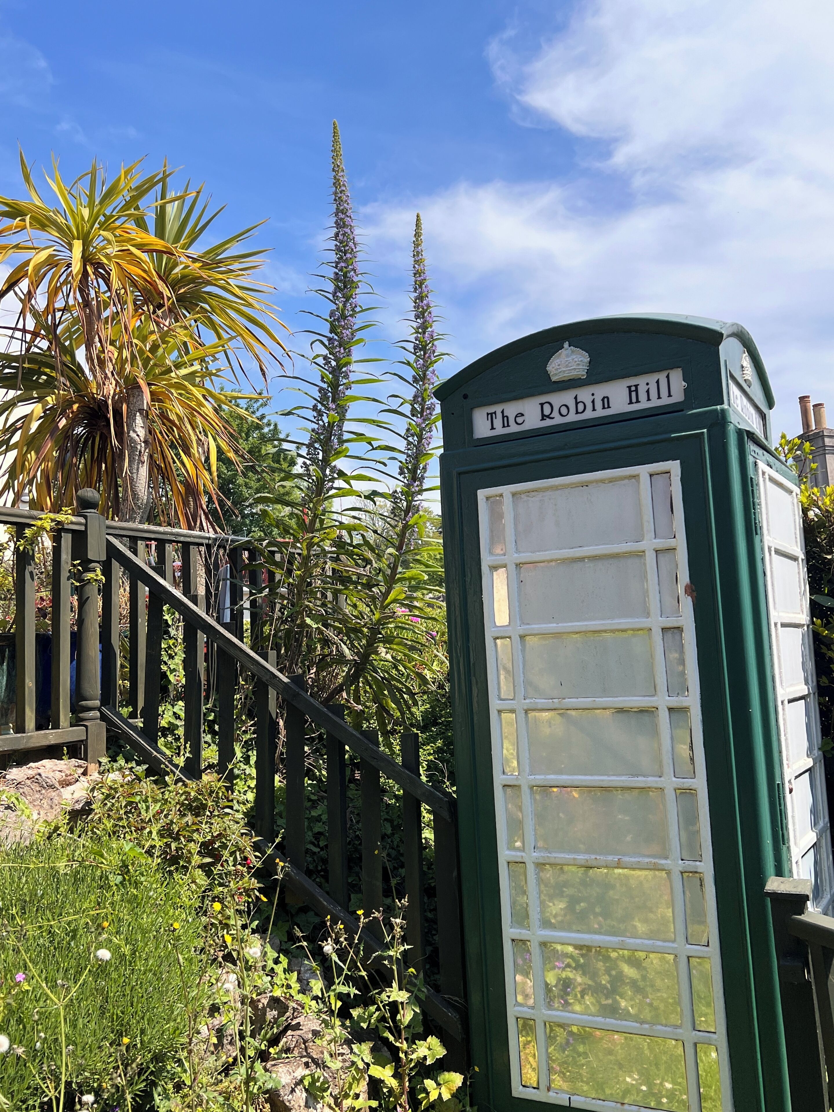 Una cabina telefónica verde con un letrero que dice 'The Robin Hill'.
