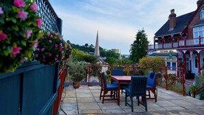 A patio with outdoor seating, a view of a church spire, and a building with a sign reading "The Robin Hill". - The Robin Hill Hotel (Torquay)