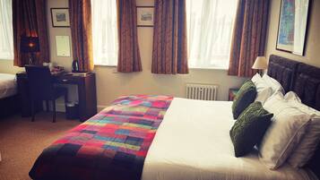 Ein Hotelzimmer mit Bett, Schreibtisch, Stuhl und Heizkörper.