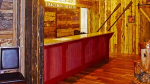 A rustic interior with wooden walls, a reception desk, and a wooden staircase.
