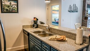 A kitchen with a granite countertop, double sink, and dark blue cabinets.