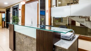 Un comptoir d’accueil avec un plateau en verre, un revêtement mural en bois et une plante.