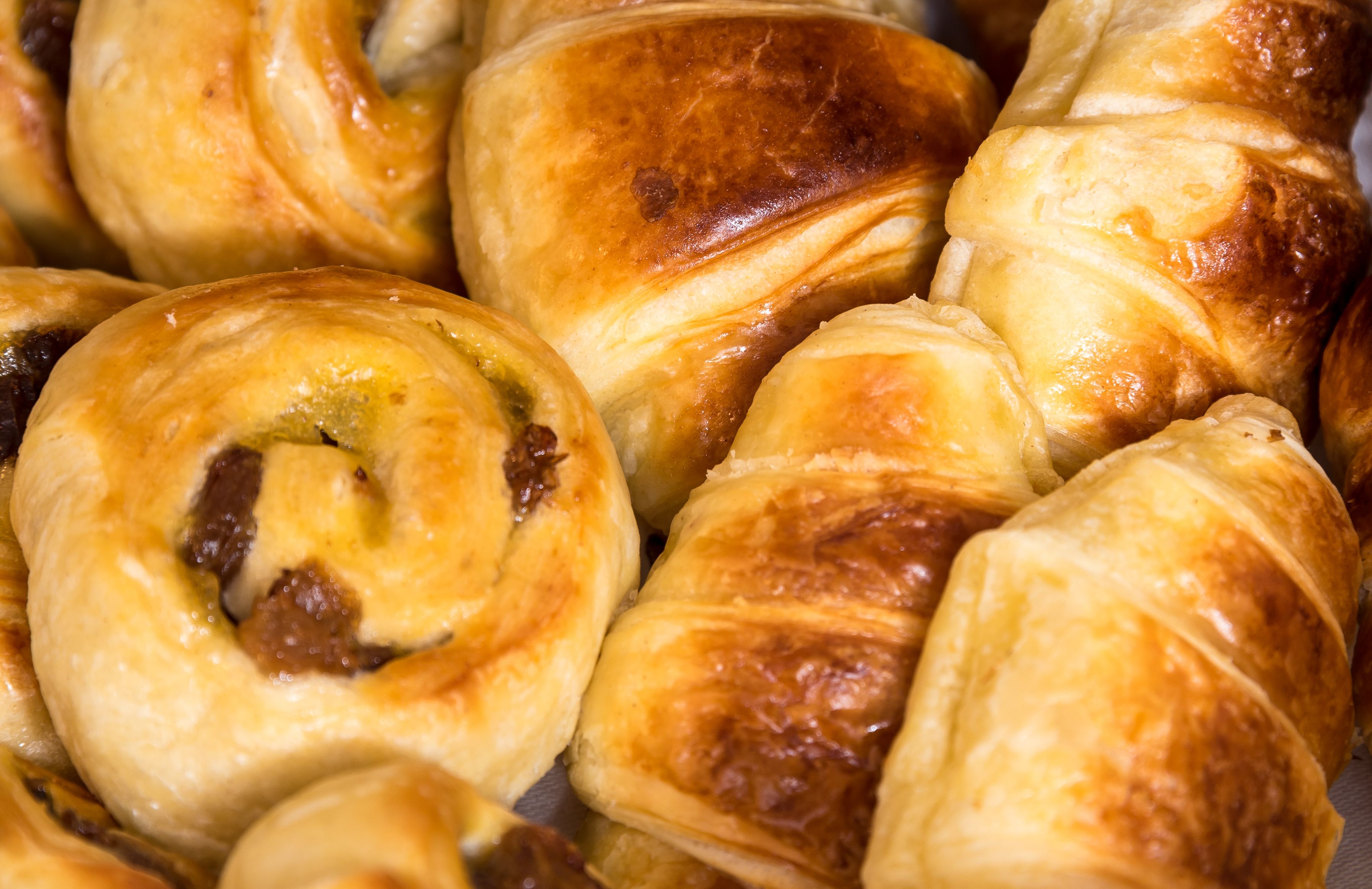 Gros plan sur différentes pâtisseries, notamment des croissants et des pains au lait, avec des garnitures apparentes et des croûtes dorées.
