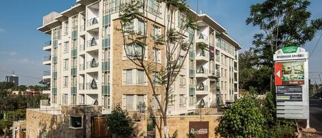 A multi-story hotel with balconies, a sign for Riverside Grove, and a landscaped garden area.
