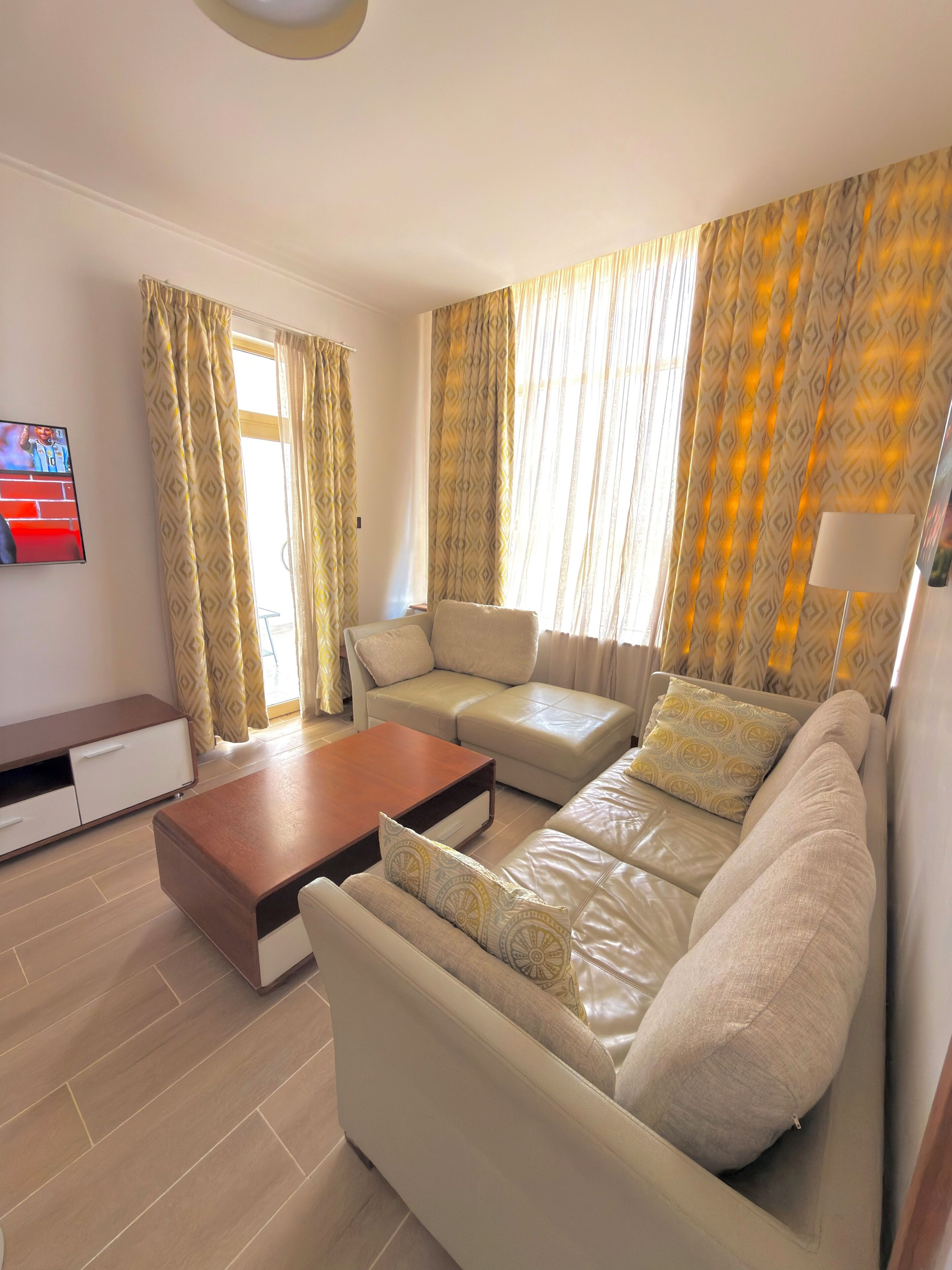 A modern living room with a sofa set, a coffee table, and a TV mounted on the wall.
