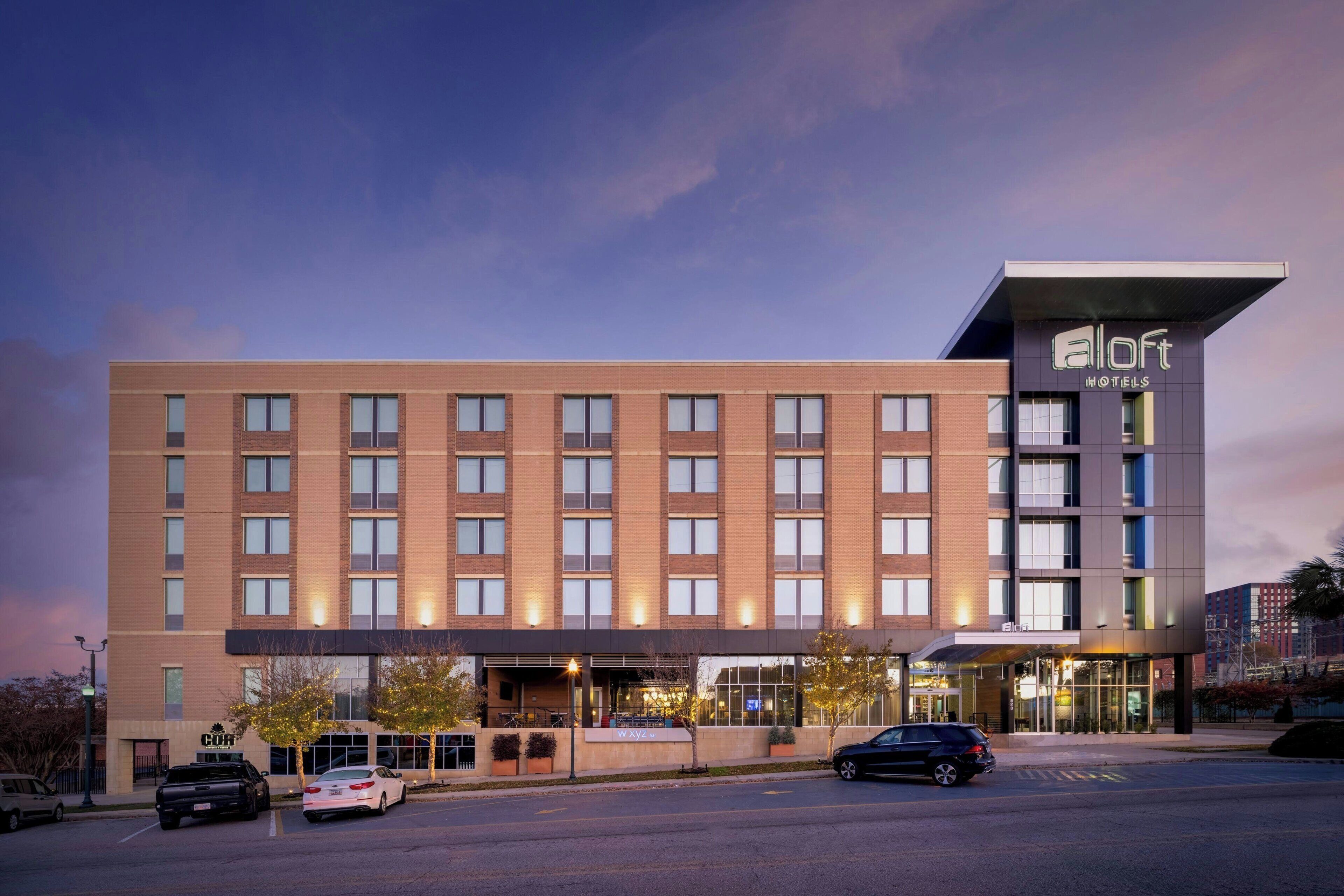 A modern hotel with a flat facade, multiple windows, and a prominent 'aloft' sign.