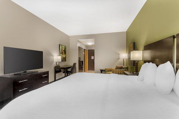 A hotel room with a large bed, a flat-screen TV, a desk with a chair, and two bedside lamps.