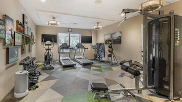 Un gimnasio con cintas de correr, máquinas de pesas y equipo de ejercicio.