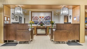 A reception area with wooden reception desks, a central counter, and a mural on the wall.