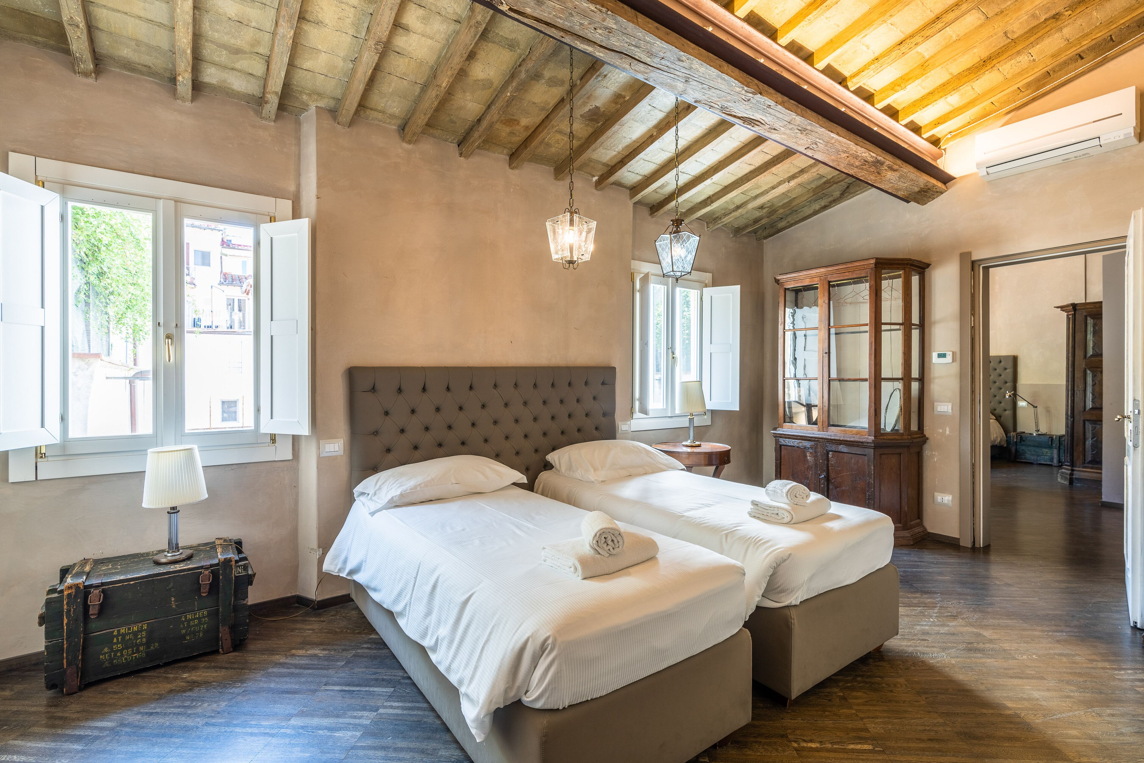 Una habitación con dos camas, techo de madera y una maleta.