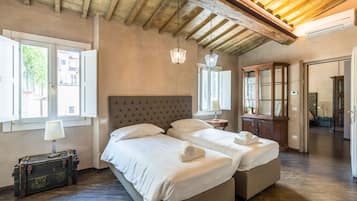 Una habitación con dos camas, techo de madera y una maleta.