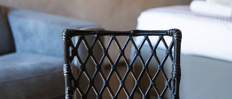 Primer plano de una silla negra tejida con un estampado de diamantes, sobre una mesa con superficie marrón.