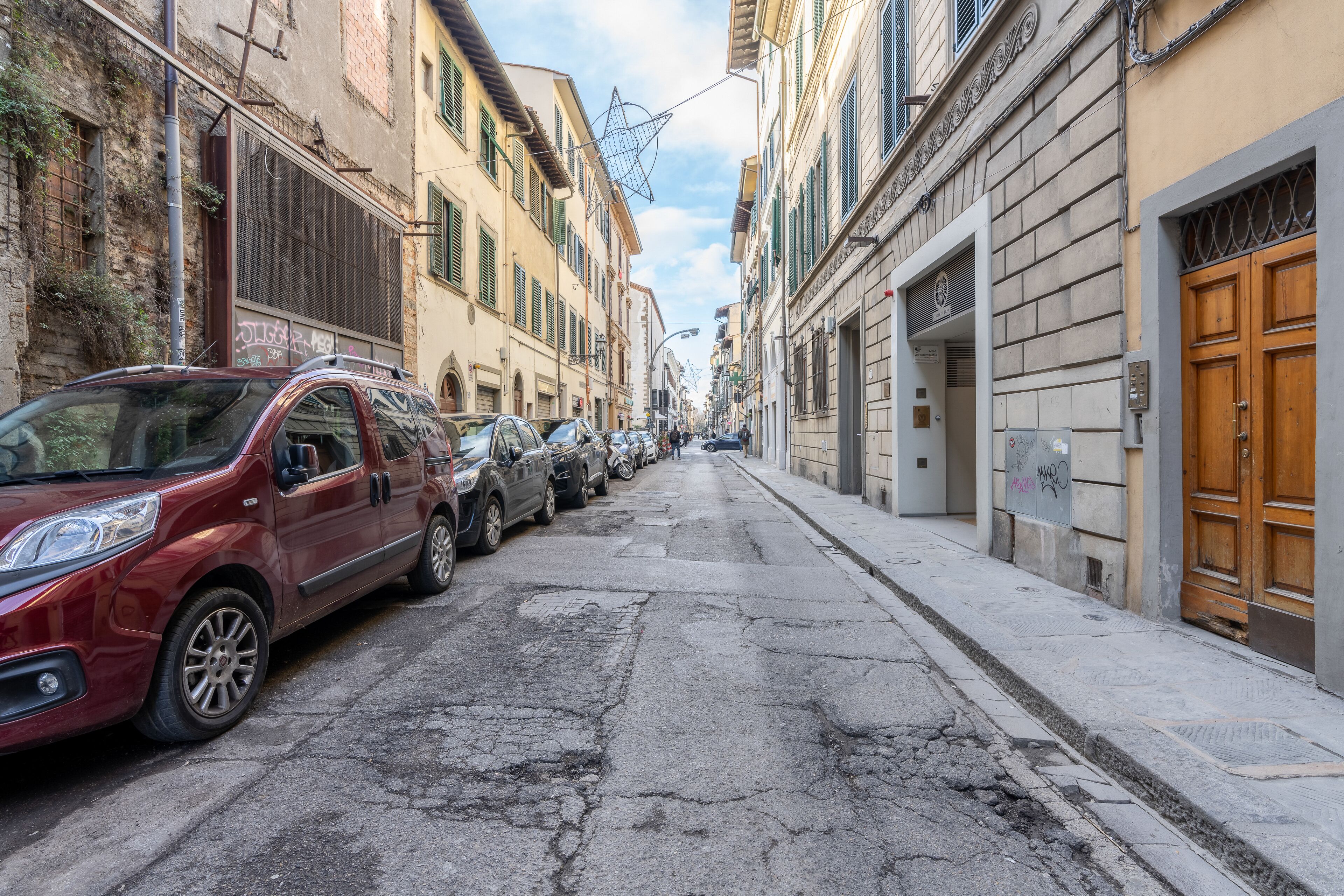 Uma rua estreita ladeada por carros estacionados e edifícios com arquitetura tradicional.
